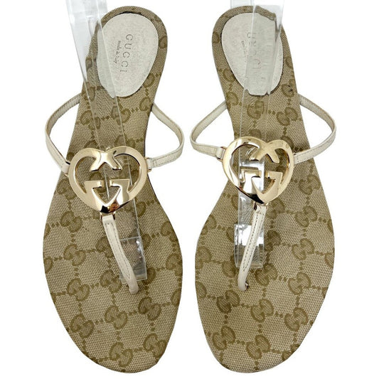 Pair of Gucci monogram sandals with heart design on a beige background